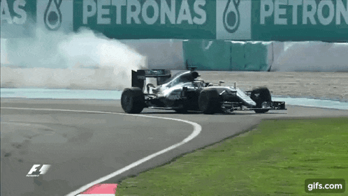 a race car is going around a curve on a track with smoke coming out of it .