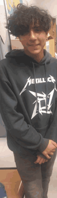 a young man wearing a metallica hoodie is smiling