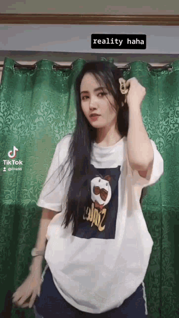 a woman is standing in front of a green curtain wearing a white t-shirt with a pringles logo on it .