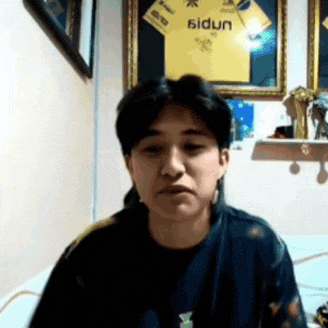 a man is sitting in front of a framed yellow shirt that says sidun
