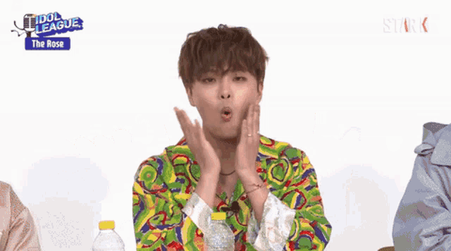 a young man in a colorful shirt is making a funny face with his hands .