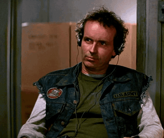a man wearing headphones and a vest that says u.s. army on it
