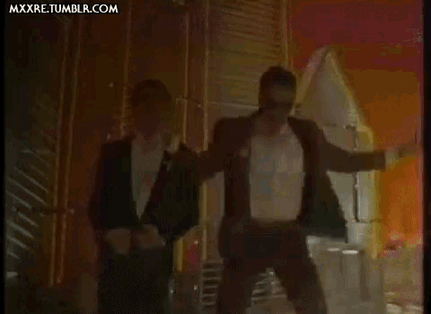 a man in a tuxedo is standing next to another man in a tuxedo in a dark room .