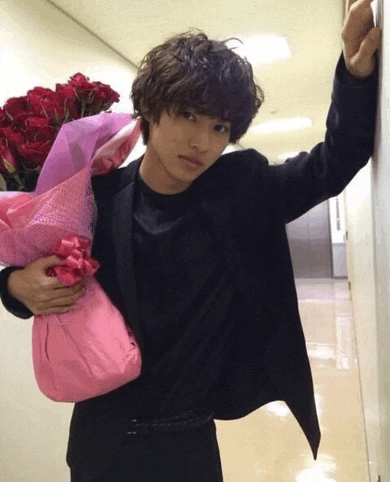 a man in a black jacket holds a bouquet of red roses