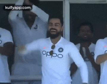 a man with a beard wearing a white shirt is dancing in front of a group of men .