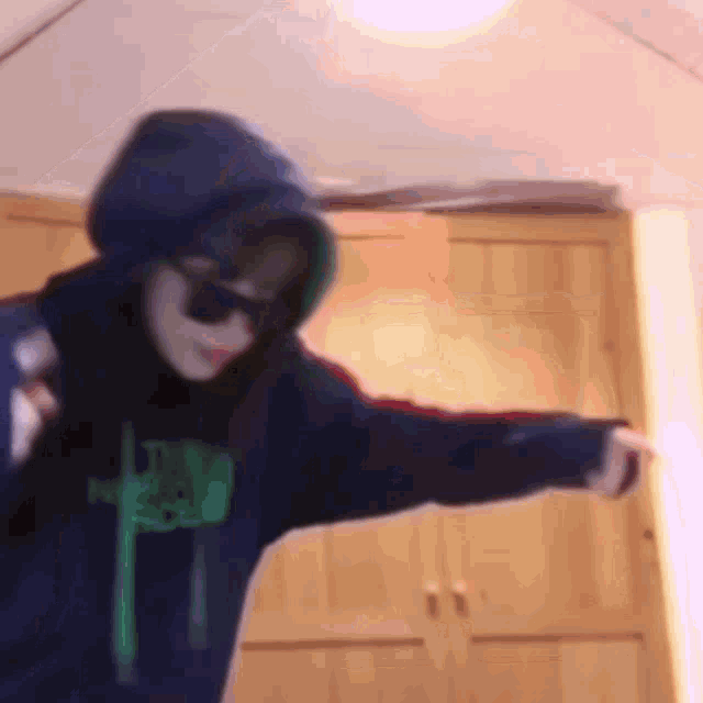 a person wearing a hoodie and sunglasses has a green letter f on the front
