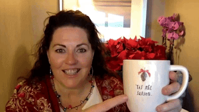 a woman holding a mug that says tis the season on it