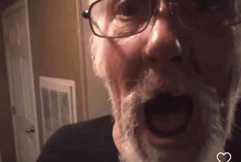a man with glasses and a white beard has his mouth open