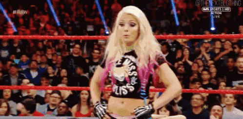 a woman is standing in a wrestling ring in front of a crowd of people .