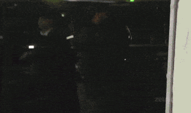 a blurred image of a person standing in front of a car with a green light behind them
