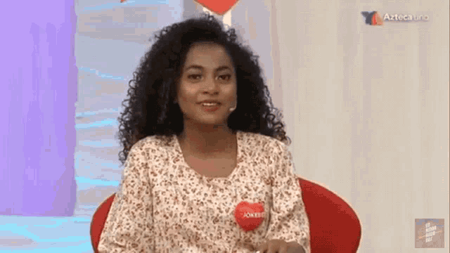 a woman sitting in a chair with a red heart on her shirt that says jokero