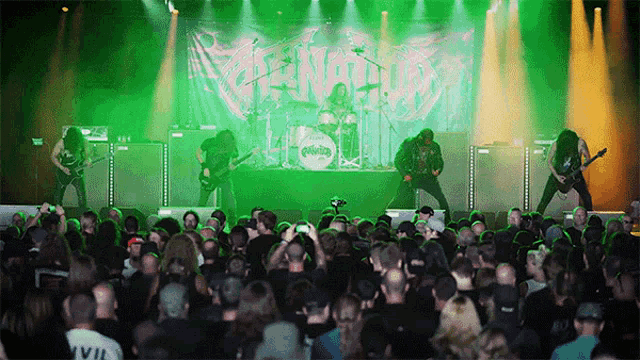 a band playing in front of a crowd with a banner that says venom