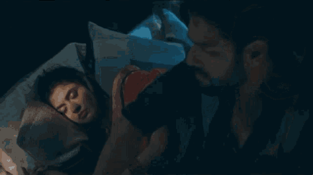 a man and a woman are sleeping in a bed together .