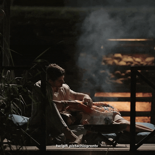 a man sits next to a woman who is laying on a blanket with the hashtag tw/gif pistachiogrentv