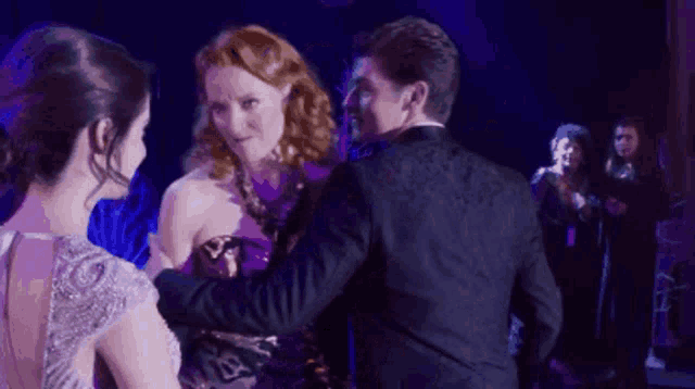 a man in a tuxedo and a woman in a dress are dancing on a stage .