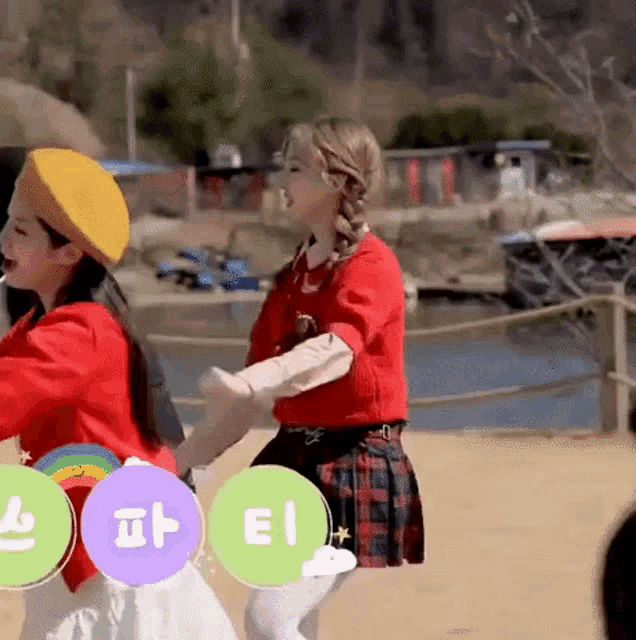 a woman in a red sweater and a yellow beret is dancing with another woman .