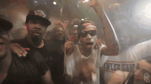 a group of men are dancing in a club and one of them is wearing a bandana .