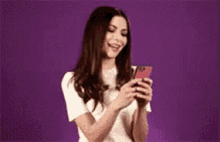 a woman is laughing while looking at her phone .