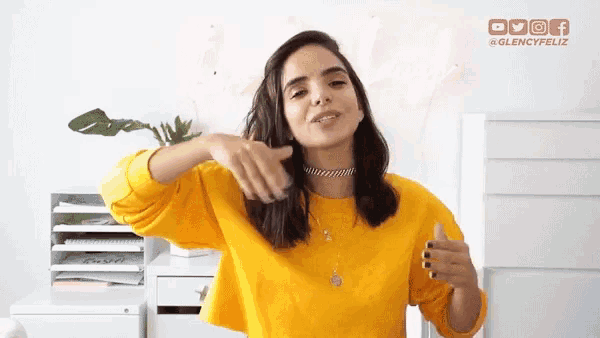 a woman in a yellow sweater is giving the thumbs up sign