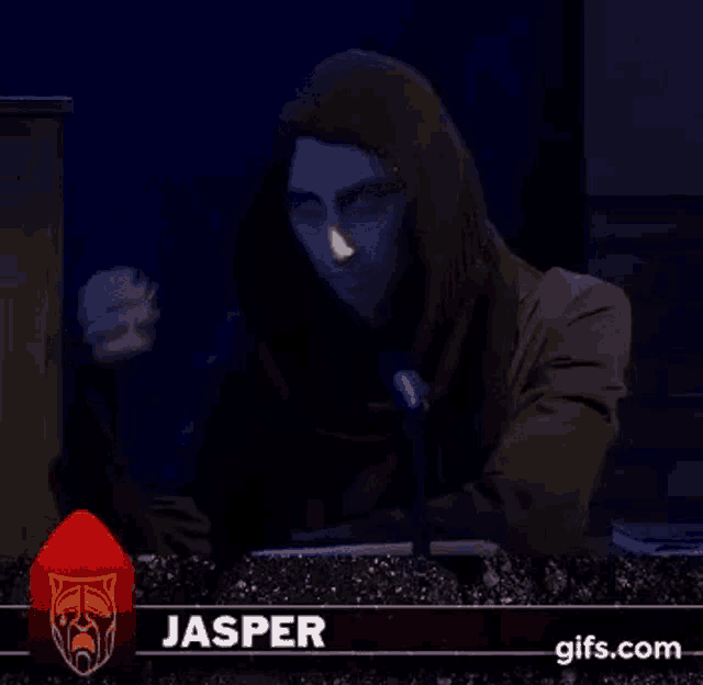 a man in a hood is sitting in front of a microphone .