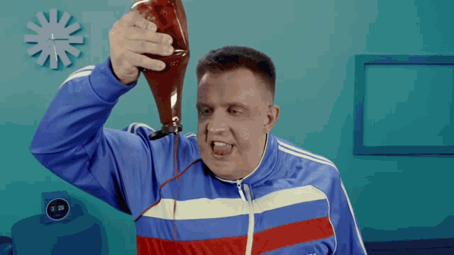 a man in a blue and red adidas jacket is pouring ketchup on his face