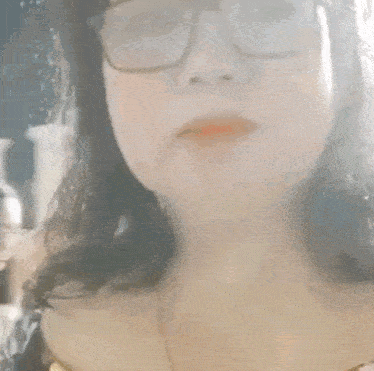 a woman wearing glasses is behind a glass with the letters fk visible