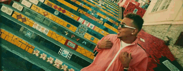 a man in a pink jacket stands in front of a set of stairs with the number 8 on the bottom