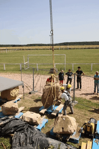 a group of construction workers are working on a large rock