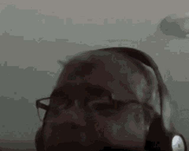 a man with glasses and headphones on his head is looking at the camera .