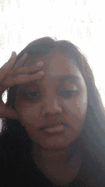 a young girl holds her hand to her forehead while looking at the camera