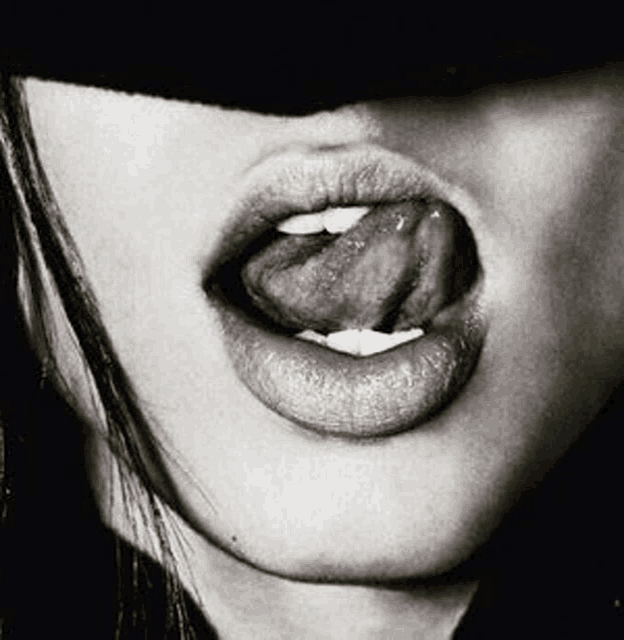 a black and white photo of a woman licking her lips .