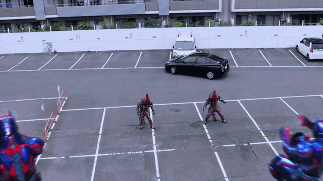 a black car is parked in a parking lot next to a couple of robots