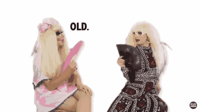 two drag queens are sitting next to each other and one of them is holding a fan and says old