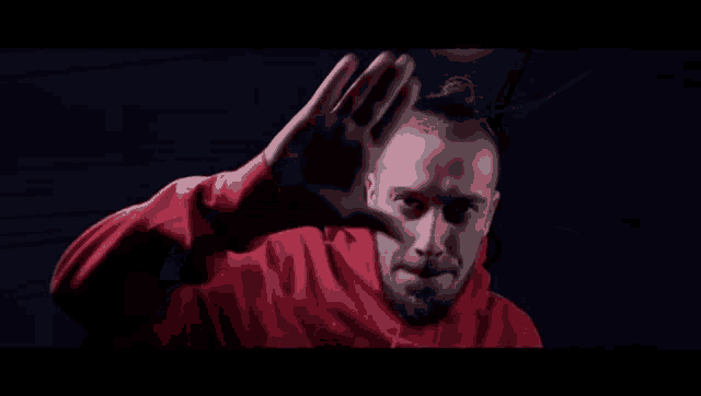 a man wearing a red hoodie is making a hand gesture