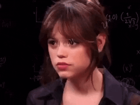 a woman is standing in front of a blackboard with math equations on her face .