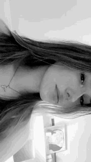 a black and white photo of a woman wearing a cross necklace