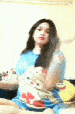 a woman is sitting on a bed with a spongebob shirt on .