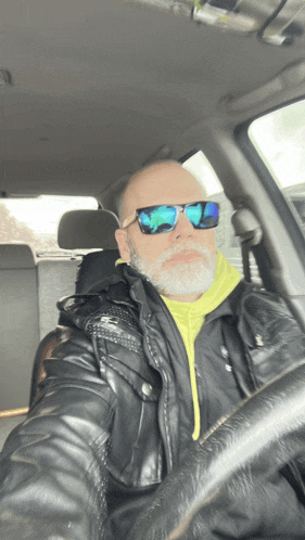 a man wearing sunglasses and a yellow hoodie is sitting in a car