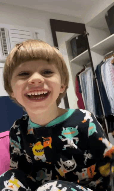 a young boy wearing a pajama top with animals on it is smiling