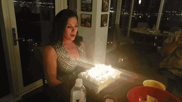a woman sitting at a table with a cake and a bottle of water that says m on it