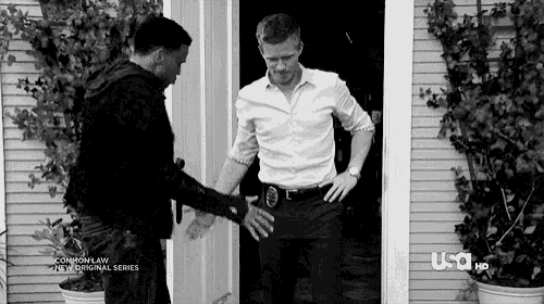 a black and white photo of two men standing next to each other in front of a door .