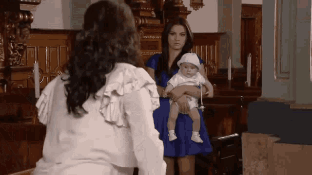 a woman in a blue dress holds a baby in a church