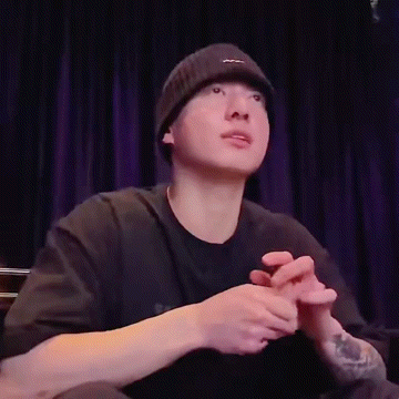 a man wearing a beanie and a black shirt is sitting on a stage .