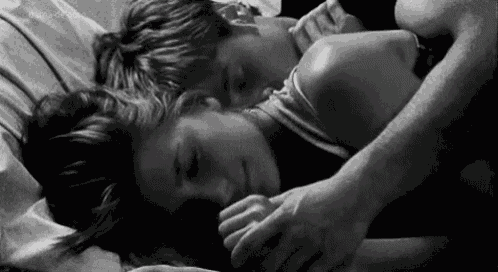 a man and a woman are sleeping in bed together .