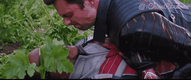 a man in a superhero costume is laying on another man 's back in the grass .