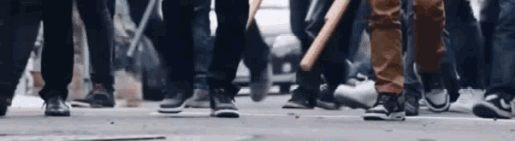 a group of people walking down a street with baseball bats in their hands .
