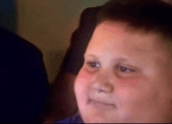 a young boy is making a funny face while looking at something .