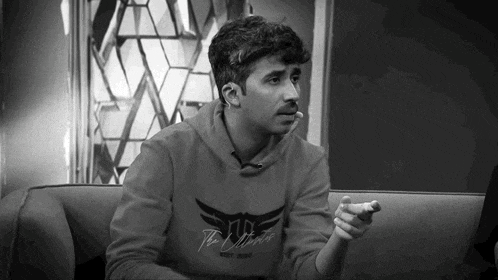 a man is sitting on a couch wearing a sweatshirt that says the ultimate
