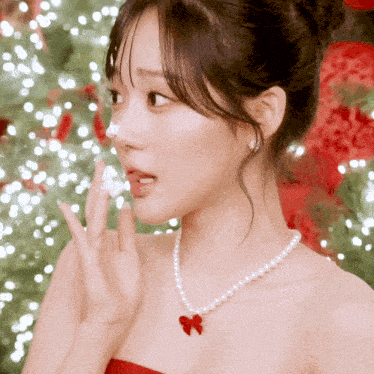 a woman wearing a pearl necklace and a red bow covering her nose