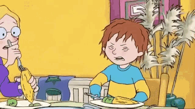 a cartoon boy is sitting at a table with a plate of food